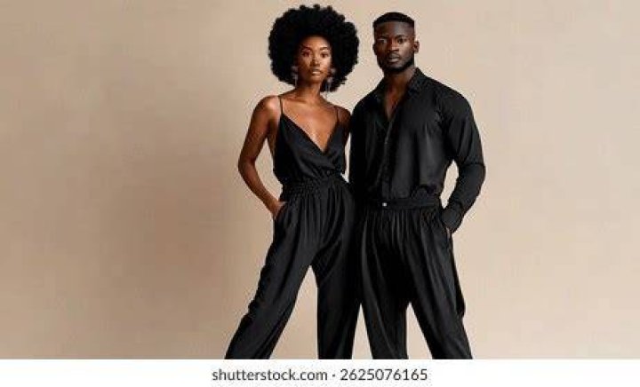 Both are dressed black while Jake is holding her and pointing to the camera.