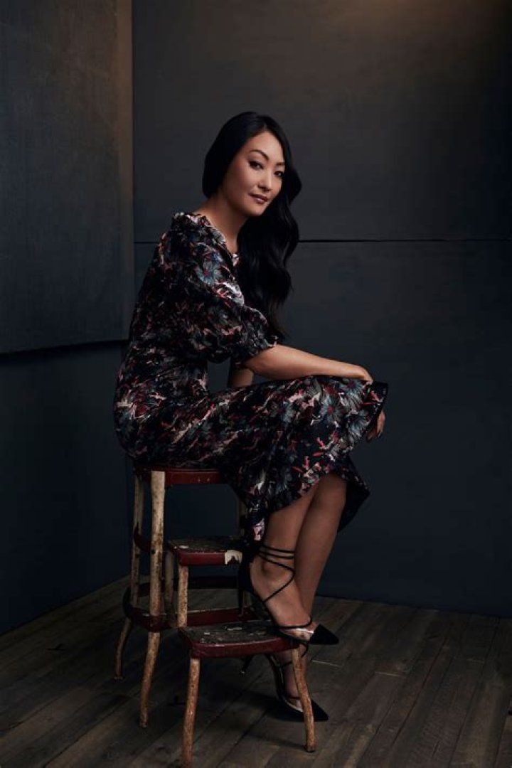 Elizabeth Anweis in a designer dress and pointed heels sitting on an artistic seat.